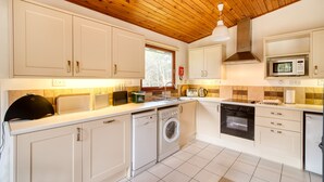 A modern kitchen with white cabinets, a washing machine, an oven, and a microwave. - Fisher - sleeps 2 guests  in 1 bedroom (Crianlarich)