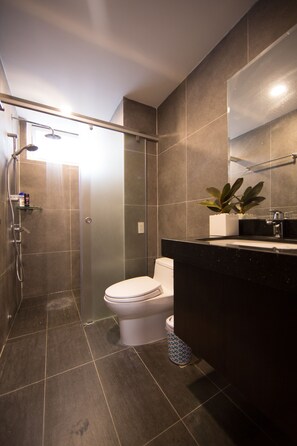 A modern bathroom with a shower, toilet, and sink.