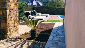 Eine Steinsäule, ein Pool und Blick auf Berge.