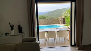 Ein Zimmer mit einer Schiebetür zu einem Außenpool, einem Sofa und einem kleinen Tisch mit Küchenutensilien.
