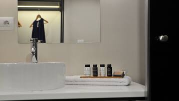 A bathroom with a white sink, a mirror, and a towel rack with toiletries.