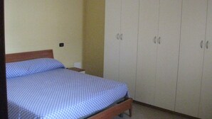A bedroom with a bed, a wardrobe, and a nightstand.