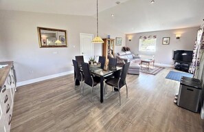 A modern living room with a dining area, a sofa, a television, and a fireplace. - Kingfisher a beautiful 5 star, 2 bedroom, 2 bathroom holiday property that can sleep up to 4 people (Crianlarich)
