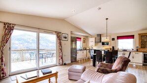 A spacious living area with a sofa, a dining table, and a kitchen in the background.