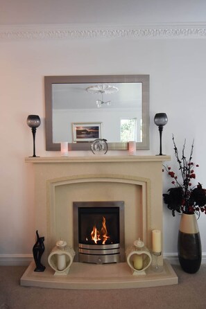 A fireplace with a mirror above it, a clock, and decorative items on the mantel. - Charming River Conwy Retreat with Stunning Views (Tal-y-cafn)