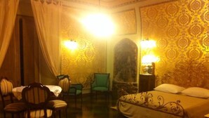 A hotel room with a bed, two chairs, a table, and two wall-mounted lamps. - B&B Savarini (Palo del Colle)