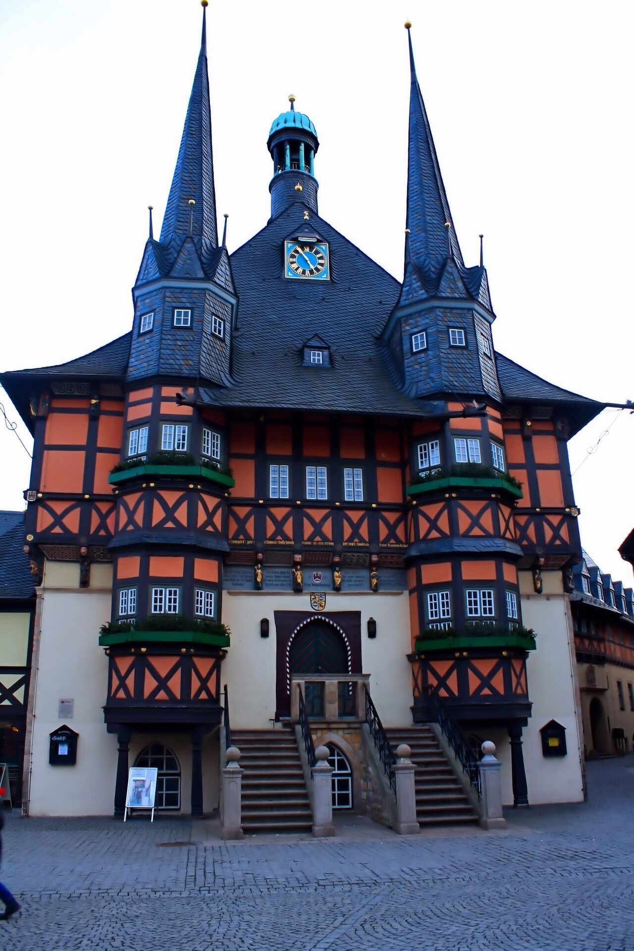 A historic building with a central clock tower, multiple towers, and a traditional facade with timber framing.