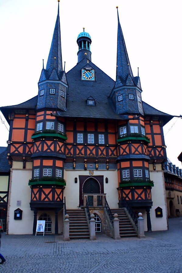 A historic building with a central clock tower, multiple towers, and a traditional facade with timber framing.