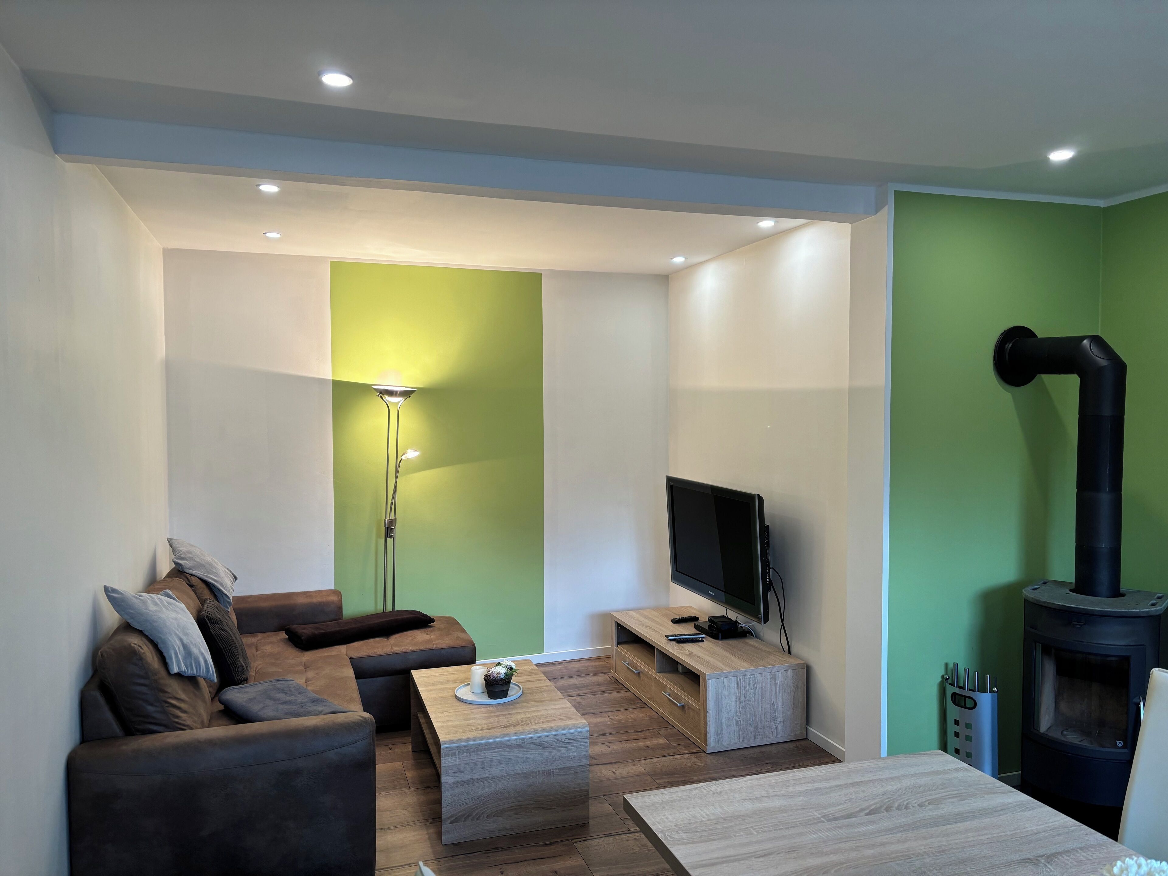 Un salon moderne comprenant un canapé, une table basse, un téléviseur et un poêle à bois.