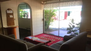 A restaurant interior with a red carpet, seating area, and a view through a glass door. - Inland Oasis Motel (Soldiers Hill)