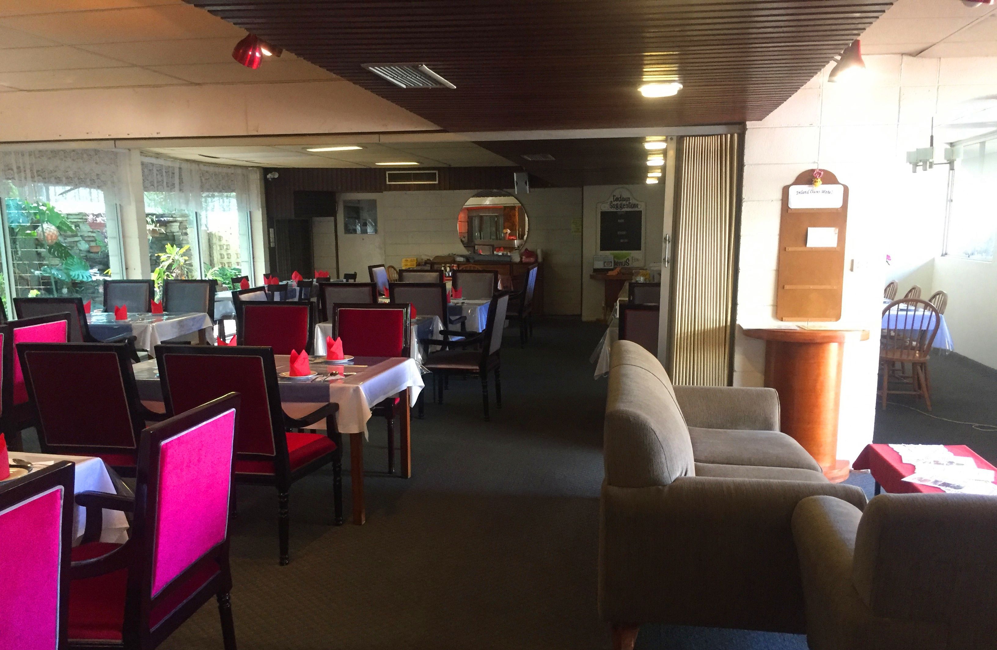 Un restaurante con mesas, sillas, una barra y un panel con la carta.