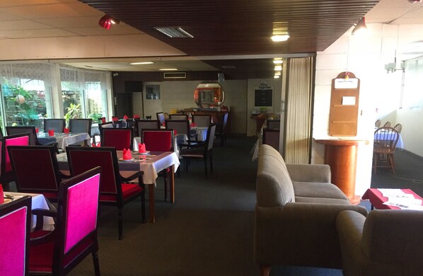 A restaurant with tables and chairs, a counter, and a menu board. - Inland Oasis Motel (Soldiers Hill)