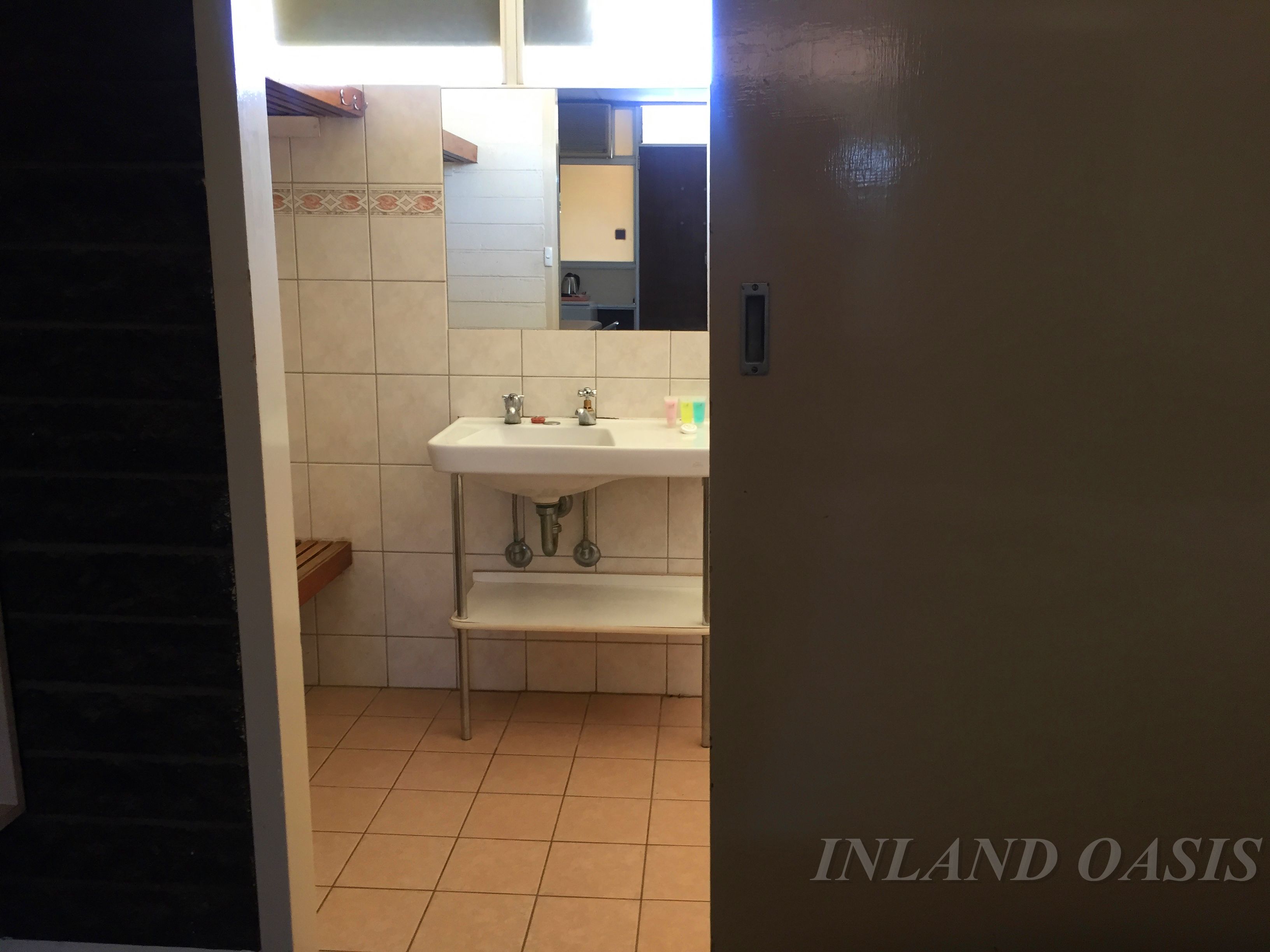 Un baño con un lavamanos blanco, un espejo y suelo de baldosas.