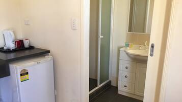 Un baño pequeño con un lavamanos blanco, espejo y ducha con puerta de cristal.