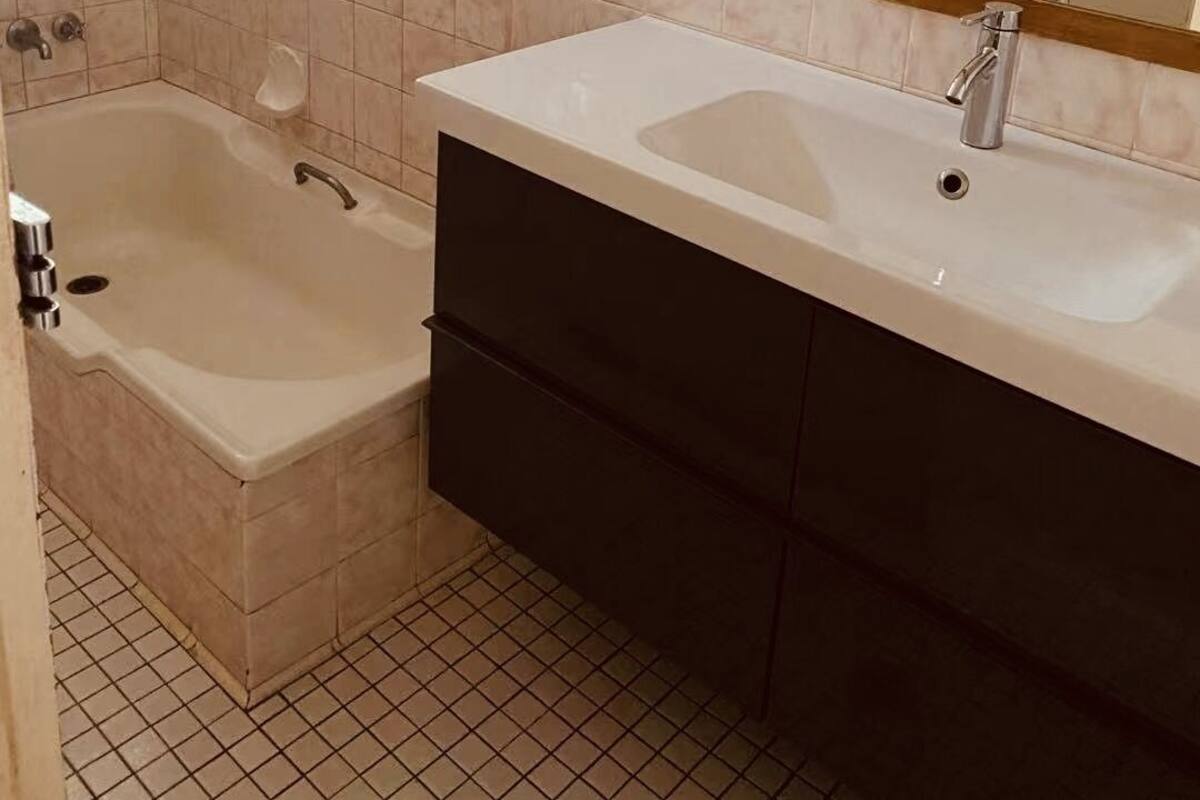 A bathroom with a bathtub, a sink, and a mirror.
