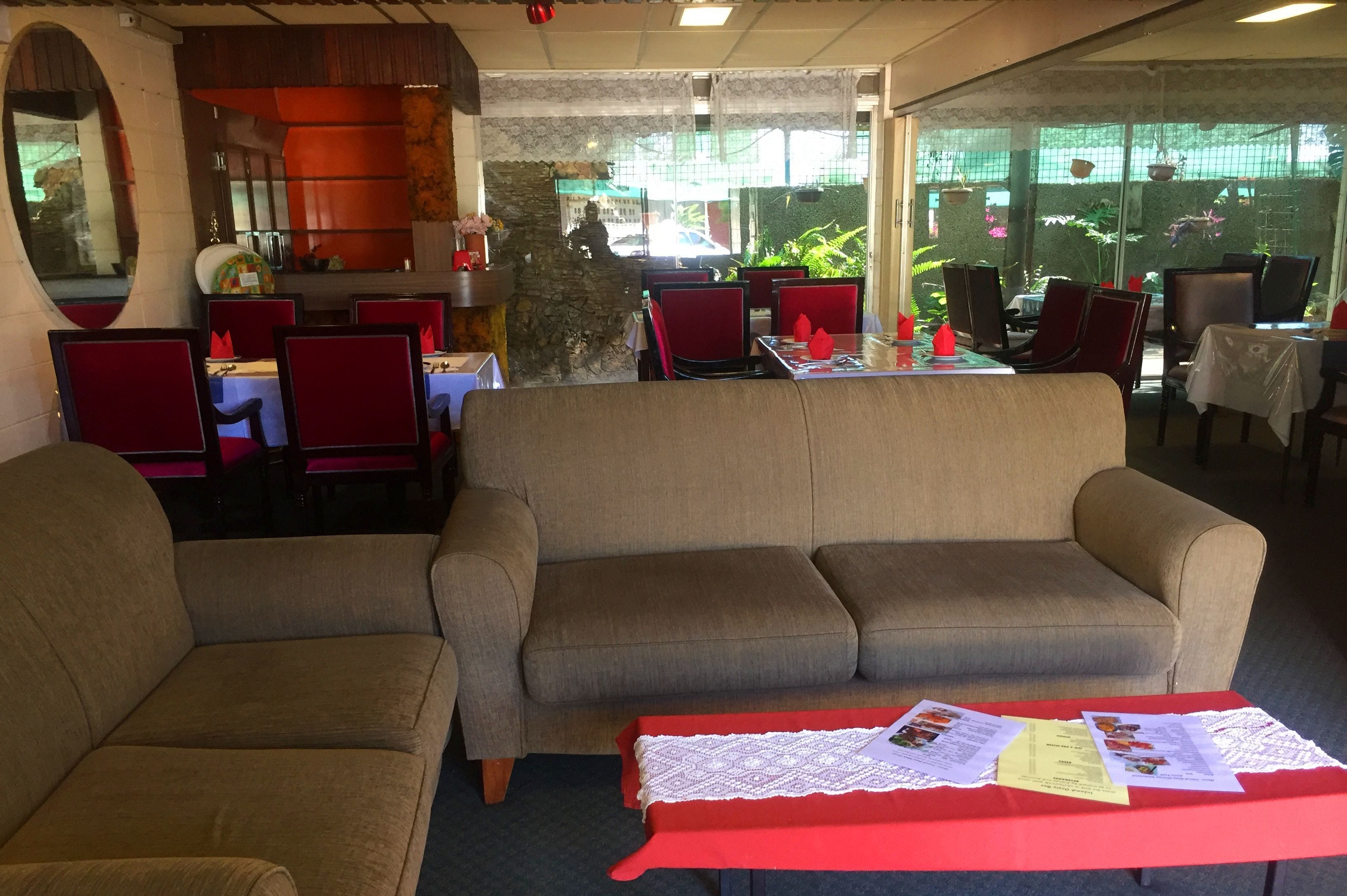 Un restaurante con una decoración en tonos rojo y beige, que incluye sofás y mesas de comedor con menús.