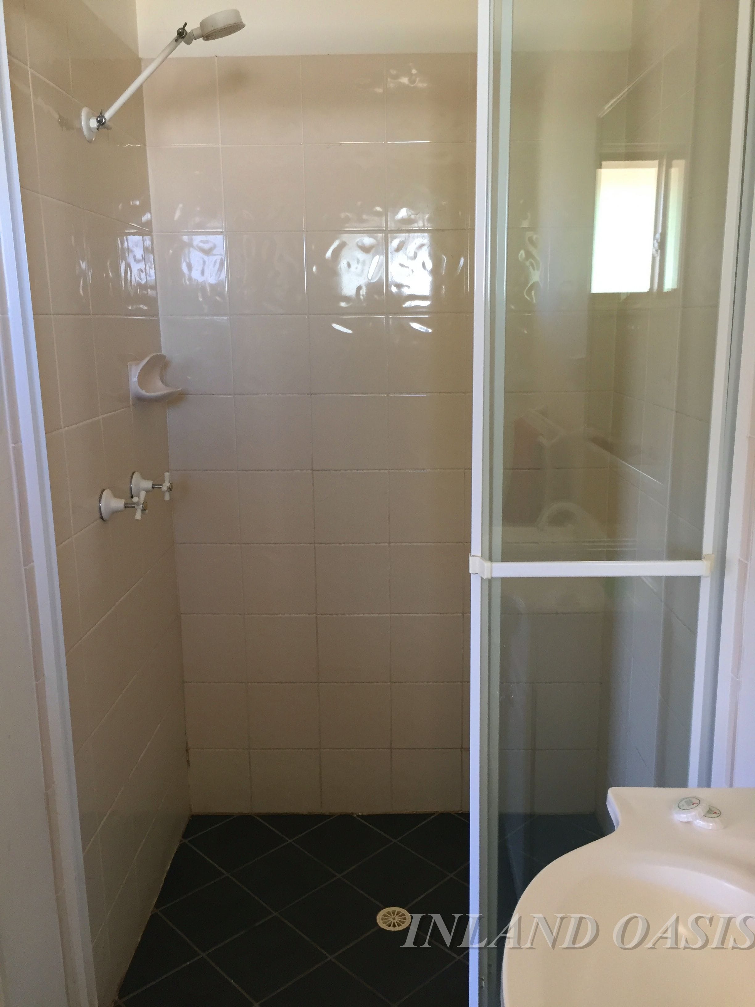Un baño con cabina de ducha de vidrio, inodoro y lavamanos.