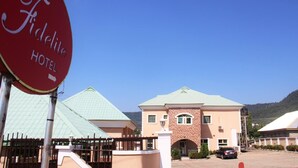 Een hotel genaamd 'Fidelite Hotel' met een bakstenen gevel, een groen dak en een parkeerplaats met auto's.
