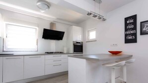Une cuisine moderne avec des meubles blancs, un four encastré et un grand îlot central doté de tabourets de bar.