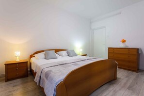 Een slaapkamer met een houten bed, twee nachtkastjes met lampen, een kaptafel en een deur.