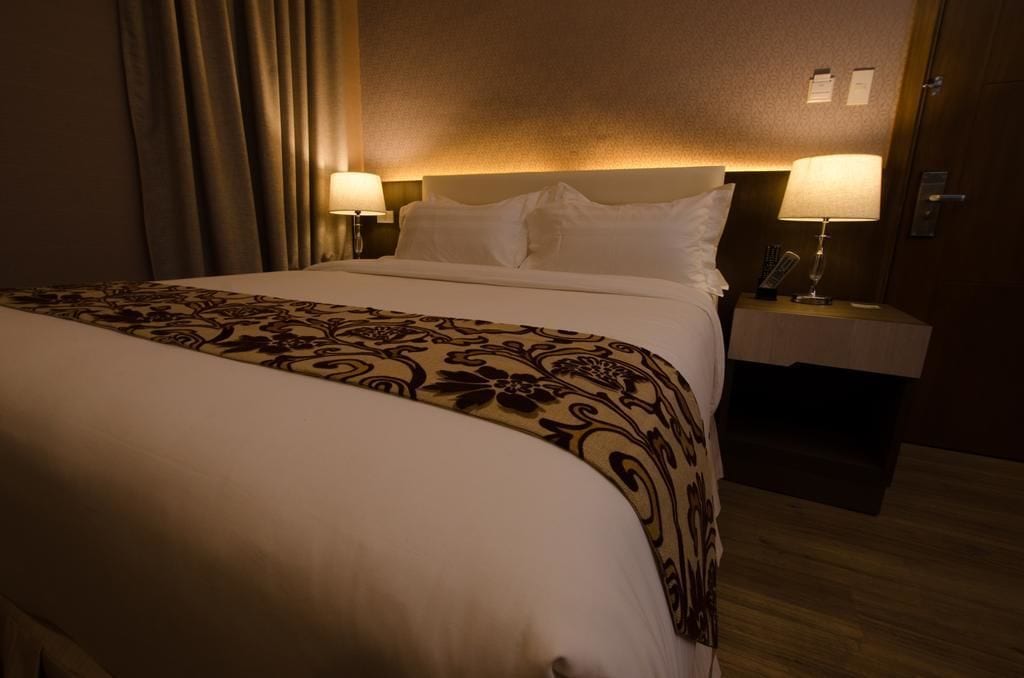 A hotel room with a large bed, two bedside tables with lamps, and a patterned bedspread.