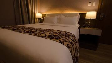 A hotel room with a large bed, two bedside tables with lamps, and a patterned bedspread.