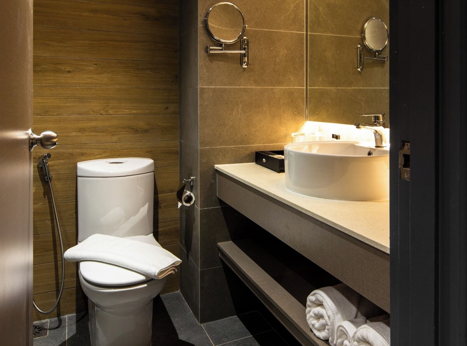A modern bathroom with a toilet, bidet, sink, and mirrors.