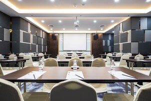 A conference room with multiple tables, chairs, a projector screen, and water bottles on the tables.