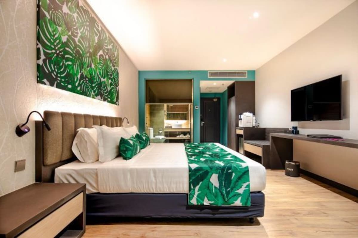 A modern hotel room with a bed, a desk, and a TV.
