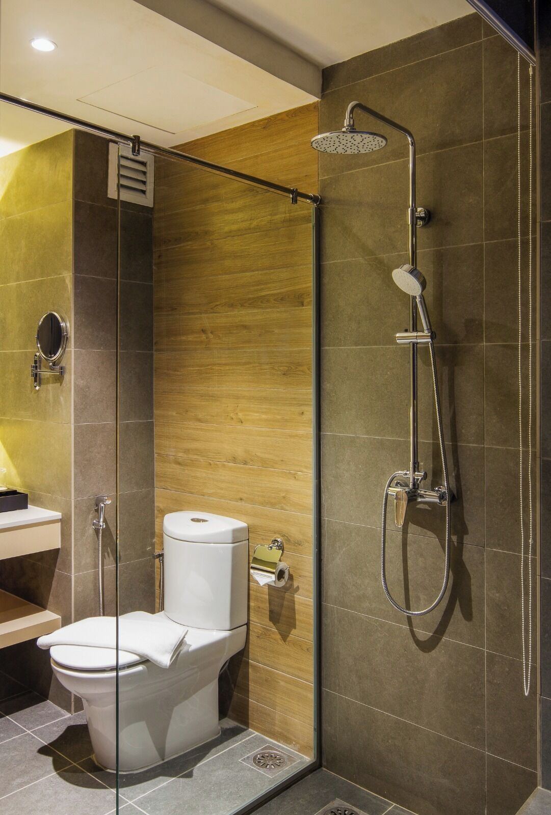 A modern bathroom with a glass-enclosed shower, a toilet, and a vanity with a mirror.