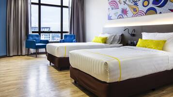 Habitación de hotel con dos camas, un ventanal con cortinas, una silla azul y una obra de arte abstracta y colorida en la pared.