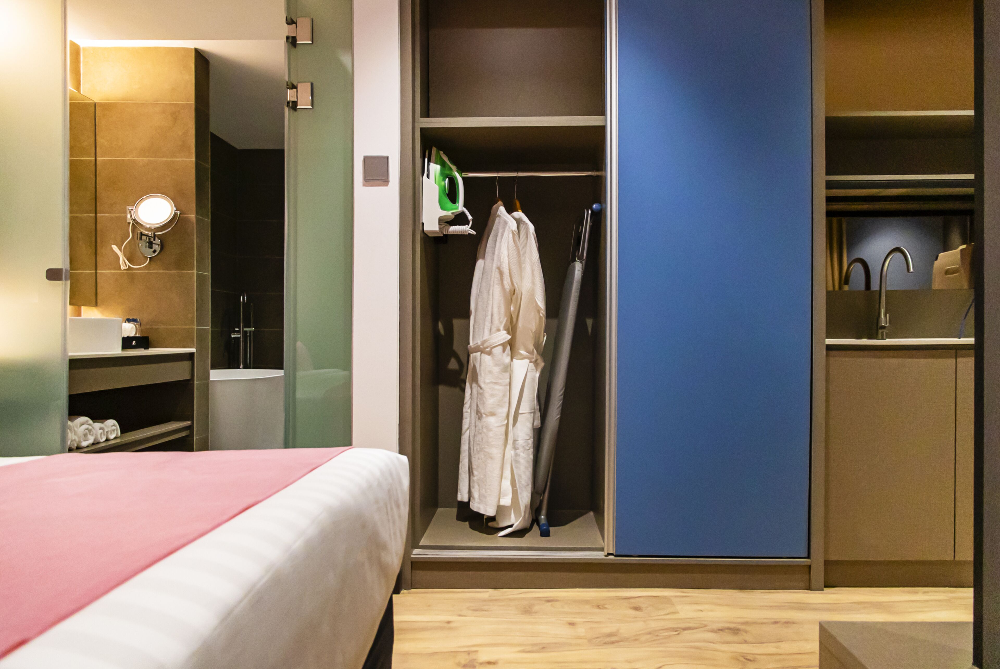 Una habitación de hotel con cama, baño, armario y espejo.