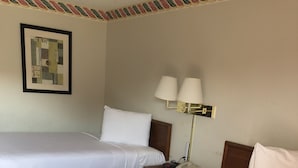 Two single beds with white linens, a bedside table with a lamp, and a framed artwork on the wall. - Rexdale Inn (Seminole)