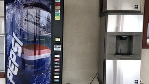 A Pepsi vending machine and a stainless steel appliance, likely a coffee maker, in an outdoor setting. - Rexdale Inn (Seminole)