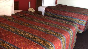 Una habitación de hotel con dos camas, un teléfono, dos lámparas y un cuadro en la pared.