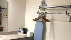 A hotel bathroom with a granite countertop, a towel rack with a blue towel, a mirror, and a wooden chair. - Rexdale Inn (Seminole)
