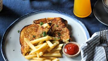 A plate with a grilled sandwich, French fries, and a small bowl of ketchup.