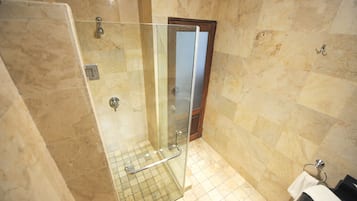 Un baño con cabina de ducha de vidrio, suelo de baldosas y puerta de madera.