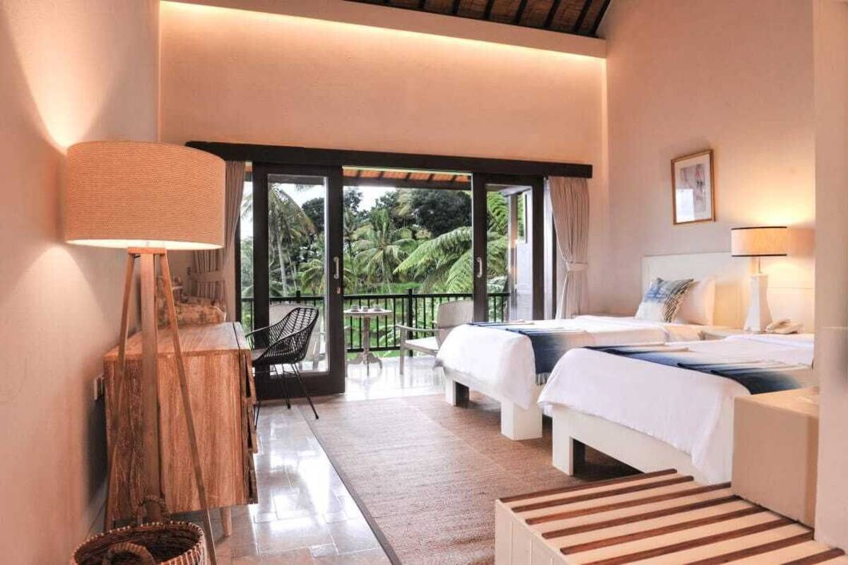 A hotel room with a balcony, a bed, a desk, and a chair.
