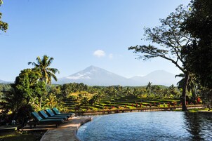 A resort with a pool, lounge chairs, and a view of a mountain.