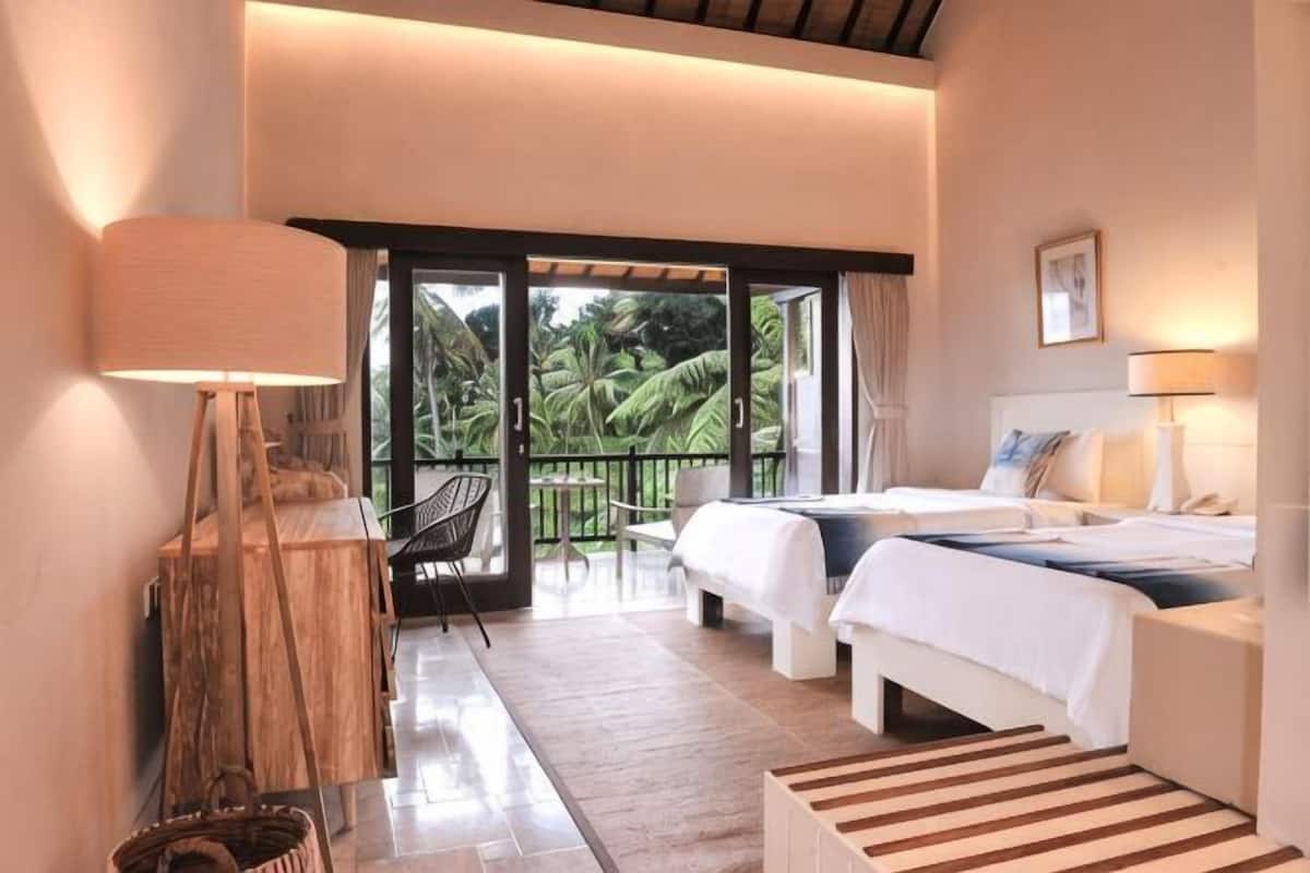 A hotel room with a bed, a desk, a chair, and a view of the outdoors.