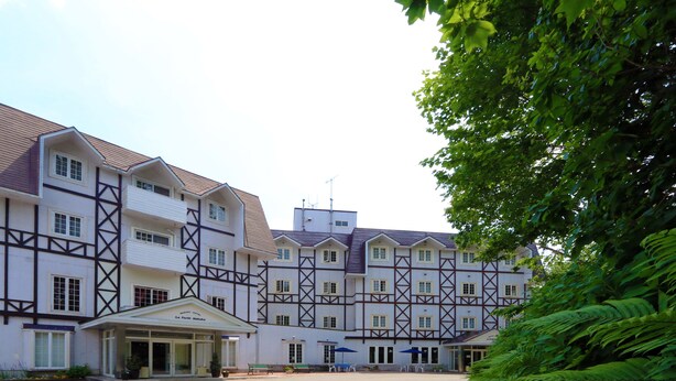 A large, multi-story hotel with a traditional European architectural style, featuring a symmetrical facade and a central entrance with a covered porch. - La Foret HAKUBA (Hakuba)