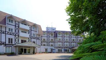 Um hotel grande, de vários andares, com arquitetura europeia tradicional, apresentando uma fachada simétrica e uma entrada central com varanda coberta.