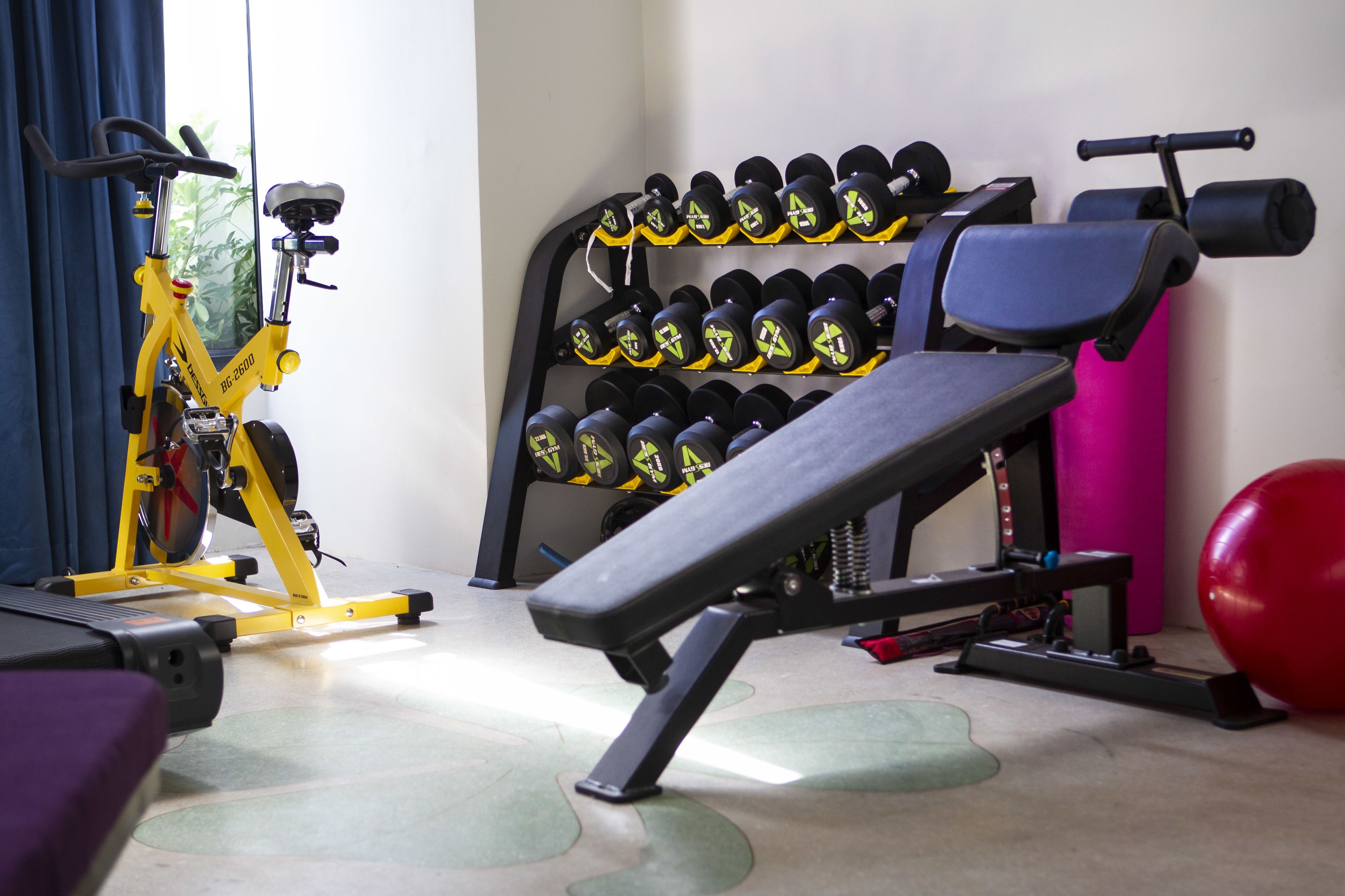 A gym with exercise equipment, including a bench, dumbbells, and a stationary bike.
