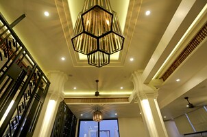 Um interior moderno com um candelabro hexagonal, uma escada com guarda-corpos pretos e um ventilador de teto.