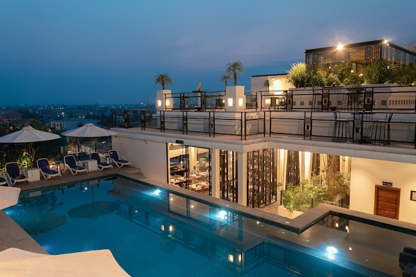 Una piscina al aire libre, sombrillas, sillones reclinables de piscina