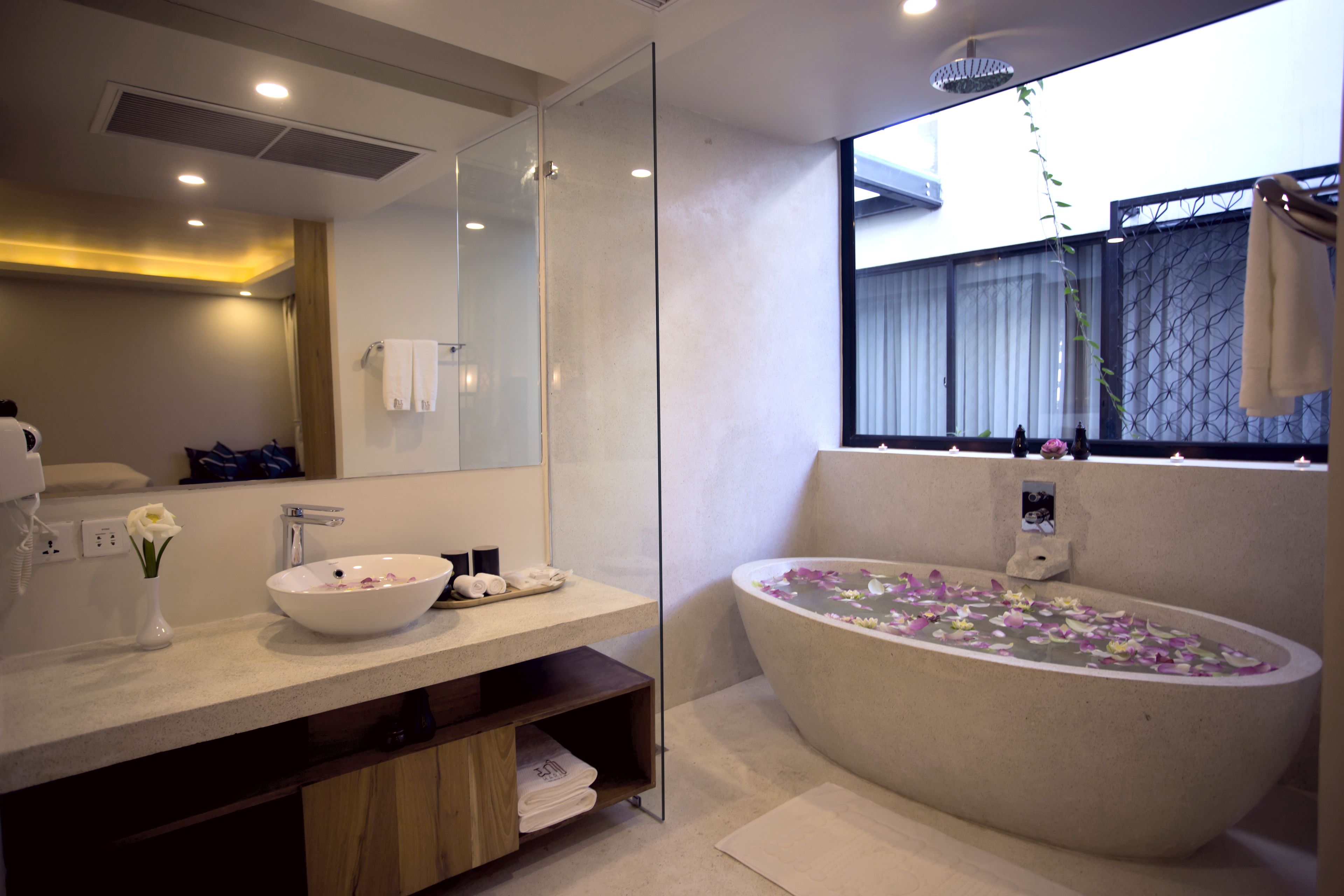A modern bathroom with a large freestanding bathtub, a vanity with a bowl sink, and a mirror above the sink.