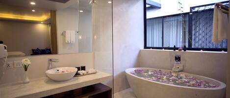 A modern bathroom with a large freestanding bathtub, a vanity with a bowl sink, and a mirror above the sink.