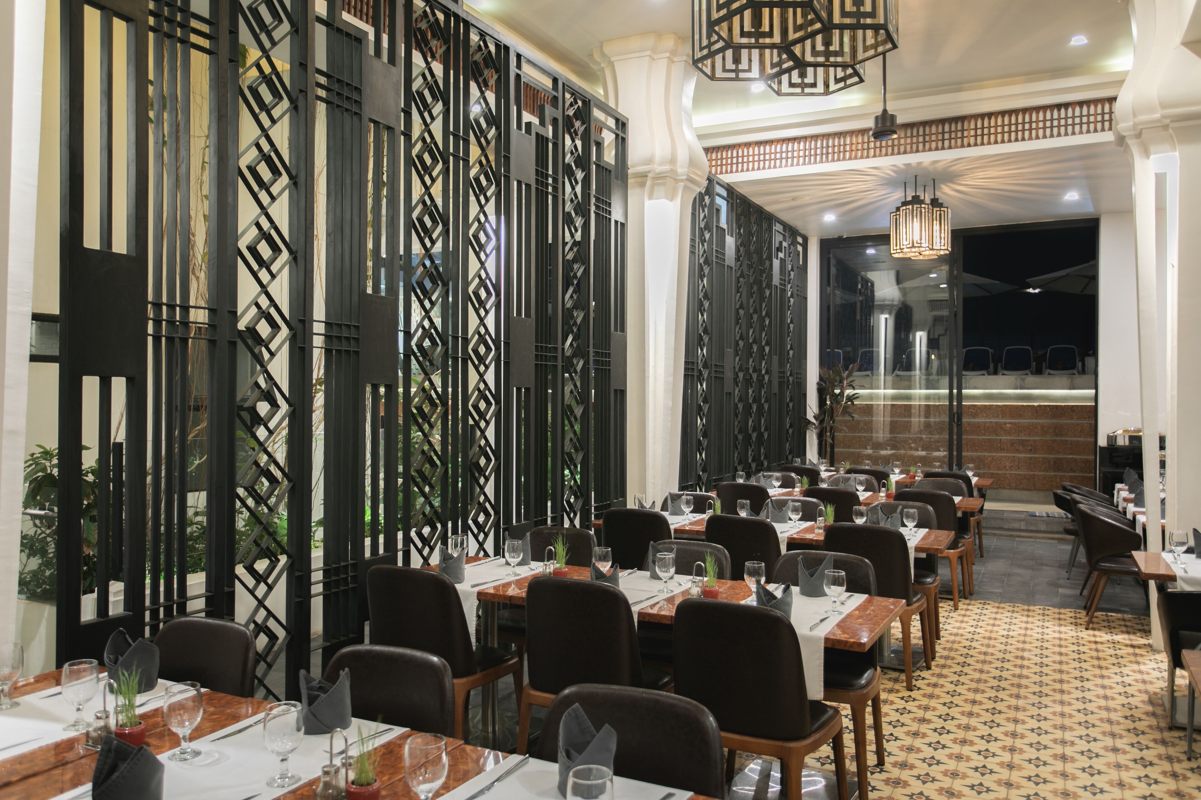 Un ristorante con diversi tavoli e sedie, un pavimento decorato e pannelli neri decorativi alle pareti.