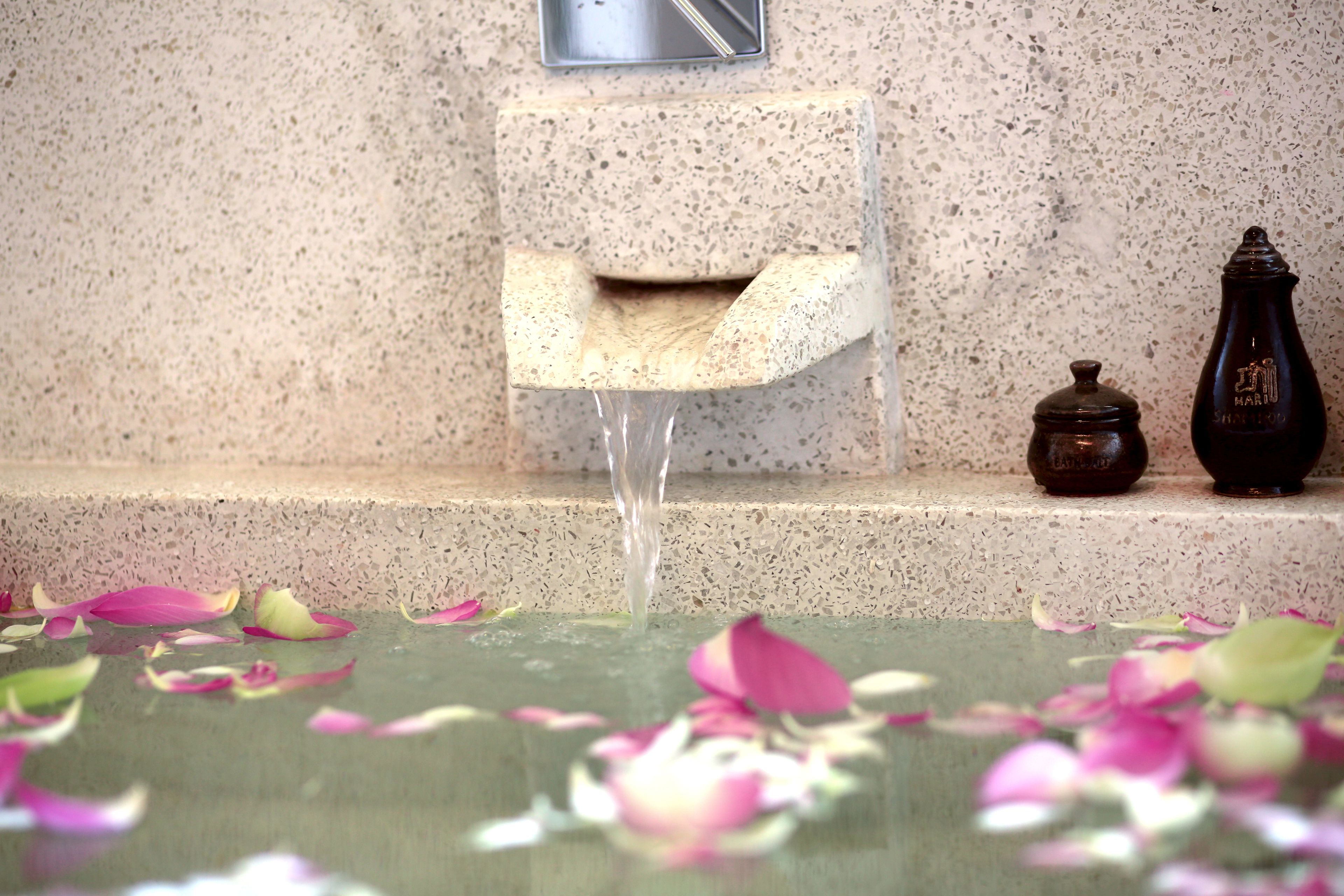 A stone wall with a water feature, a paper towel dispenser, and a bottle on a ledge.